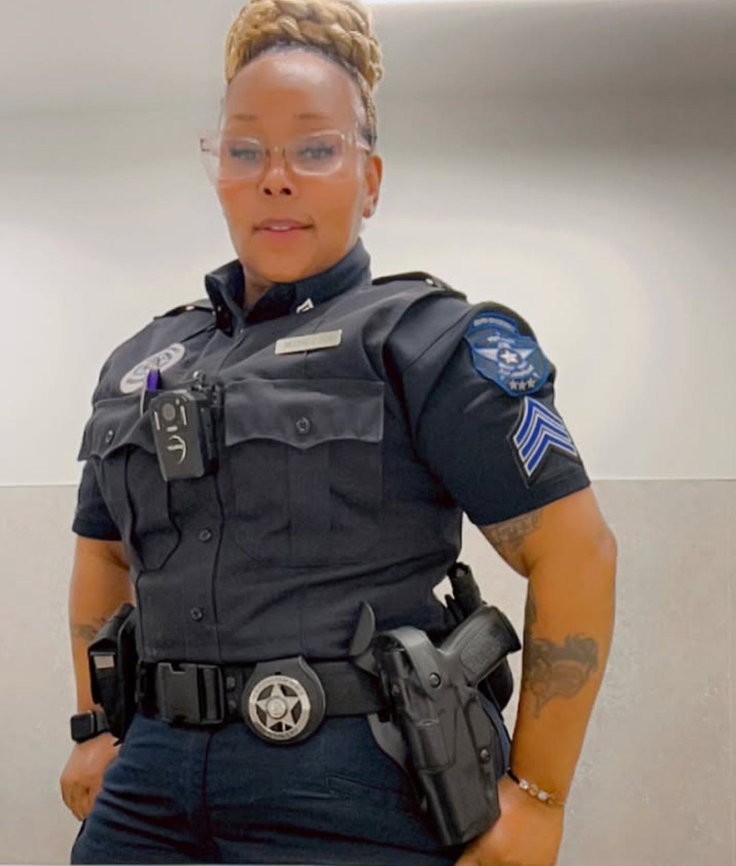 Female police officer in uniform, wearing glasses and a sidearm.