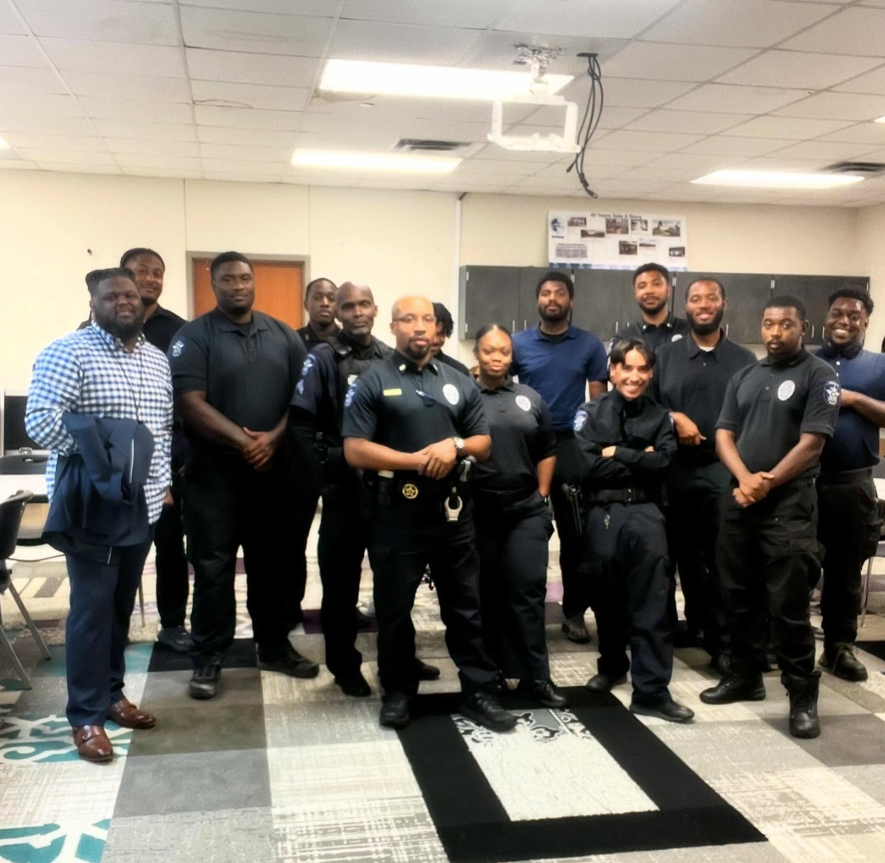 Group of police officers and one civilian stand in a classroom.