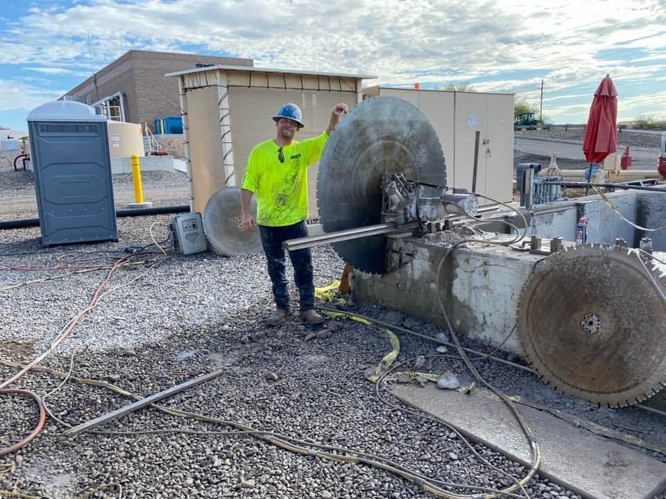 A man is standing in front of a machine that is cutting concrete.