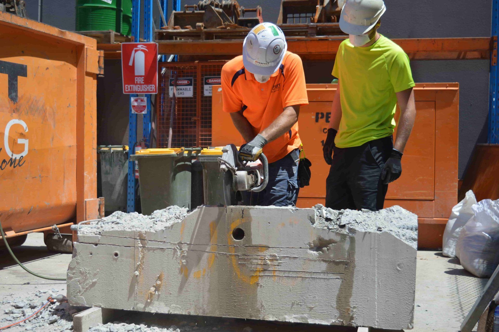Two construction workers are working on a concrete block