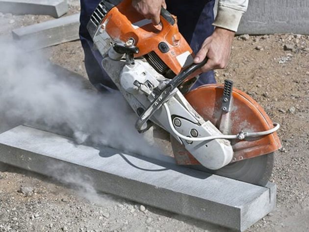 A man is using a circular saw to cut a piece of concrete