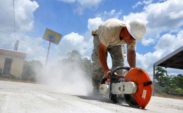 A man is using a circular saw to cut a piece of concrete