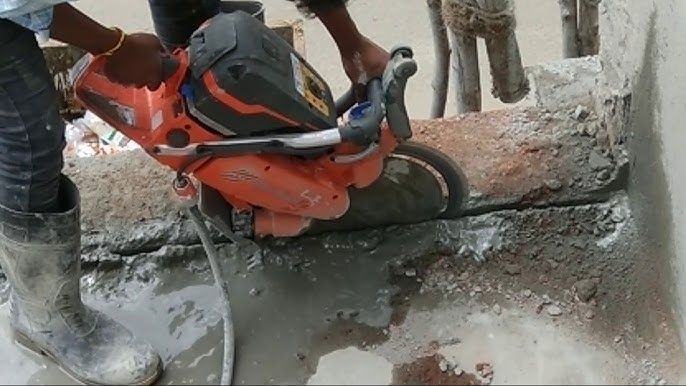 A man is using a concrete saw to cut a hole in a wall.