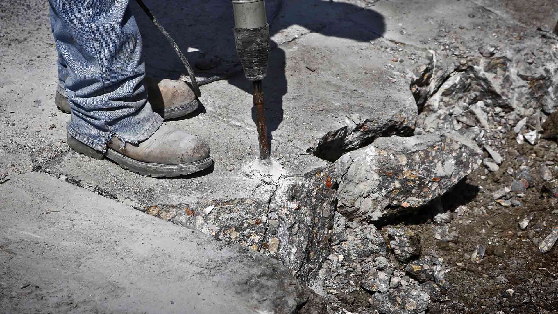 A person is using a hammer to break concrete.