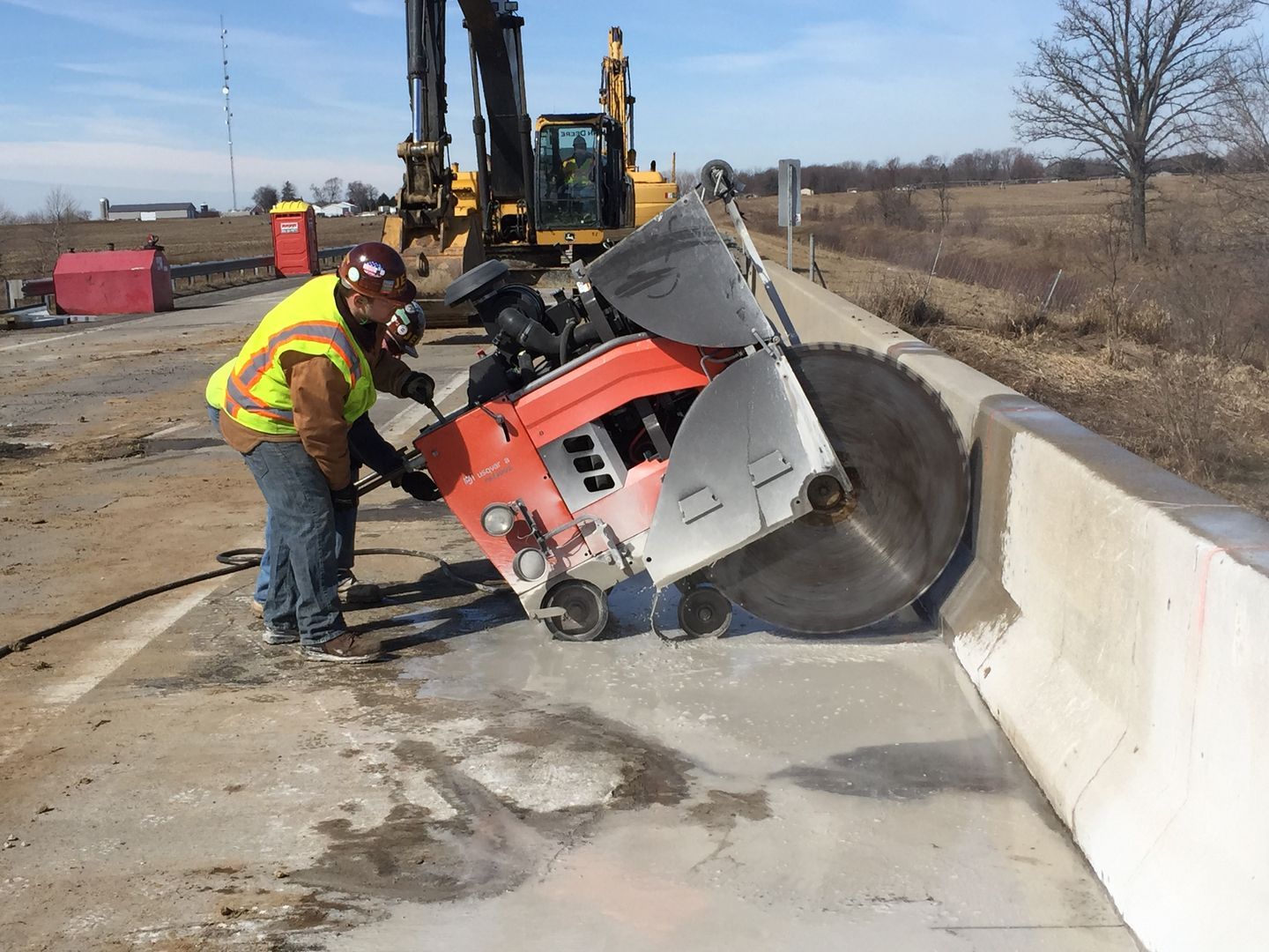 A man is using a concrete saw to cut a concrete wall