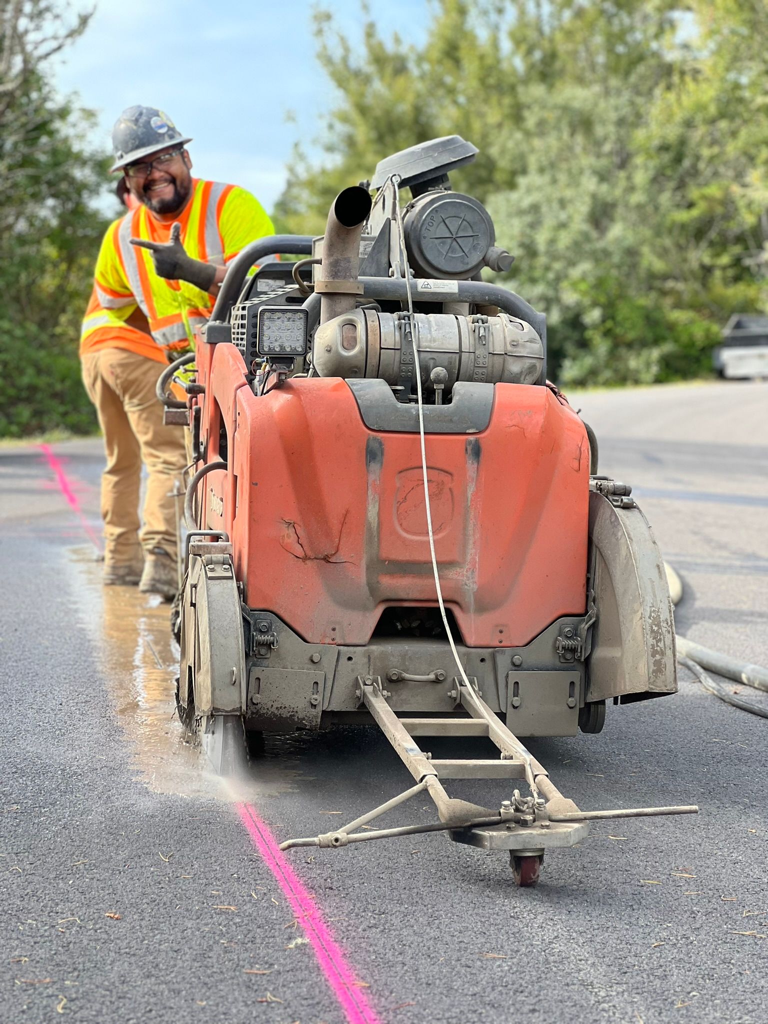 A man is using a concrete saw to cut a road.