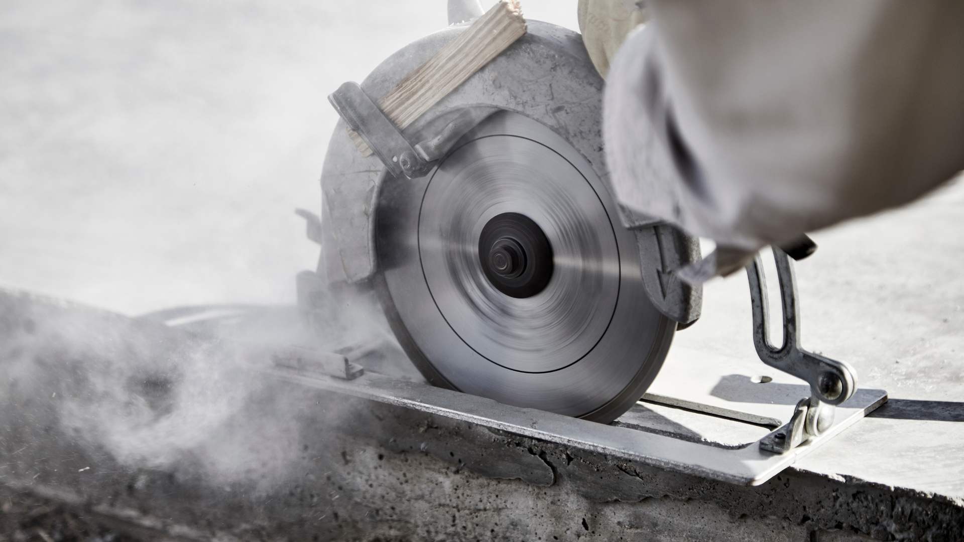 A person is using a circular saw to cut concrete.
