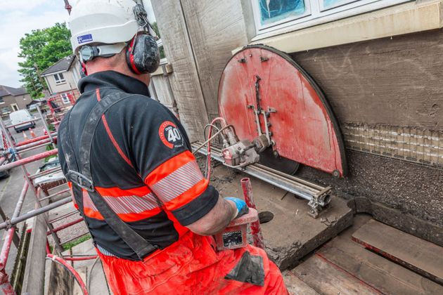 A man is using a circular saw to cut a piece of concrete