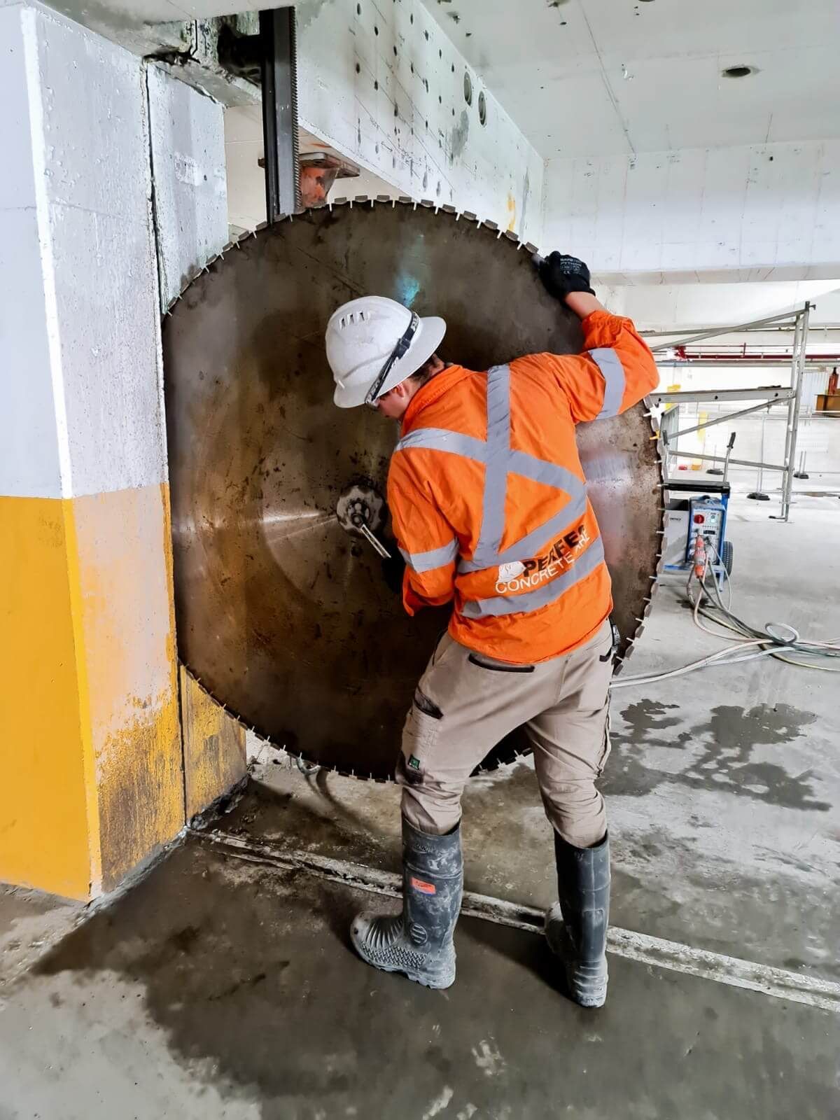 A man is cutting a hole in a wall with a large circular saw blade.