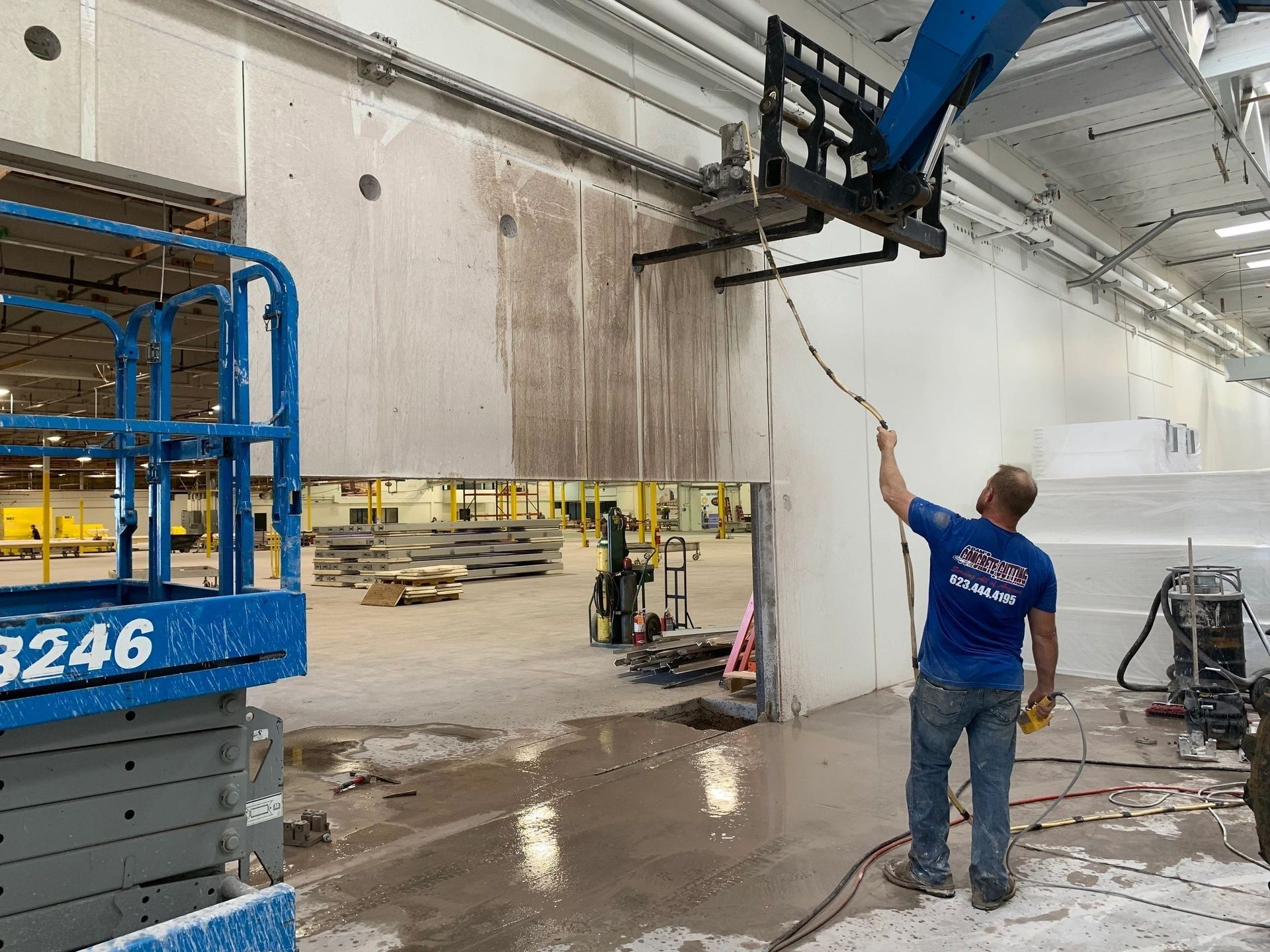 A man is cleaning a wall in a building with a hose.