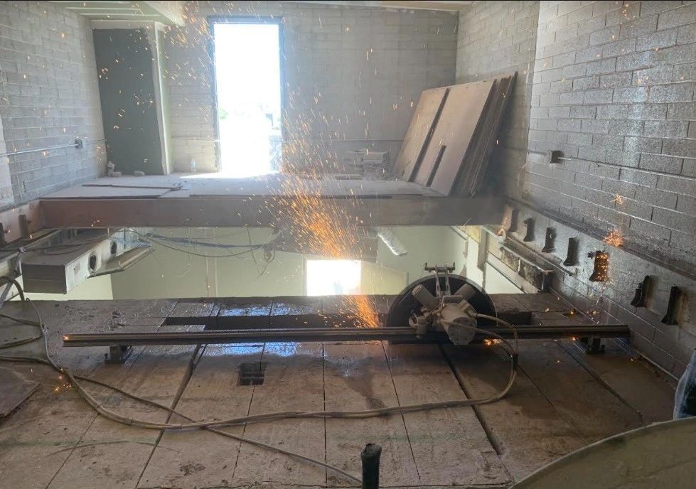 A person is cutting a piece of metal in a room with a circular saw.