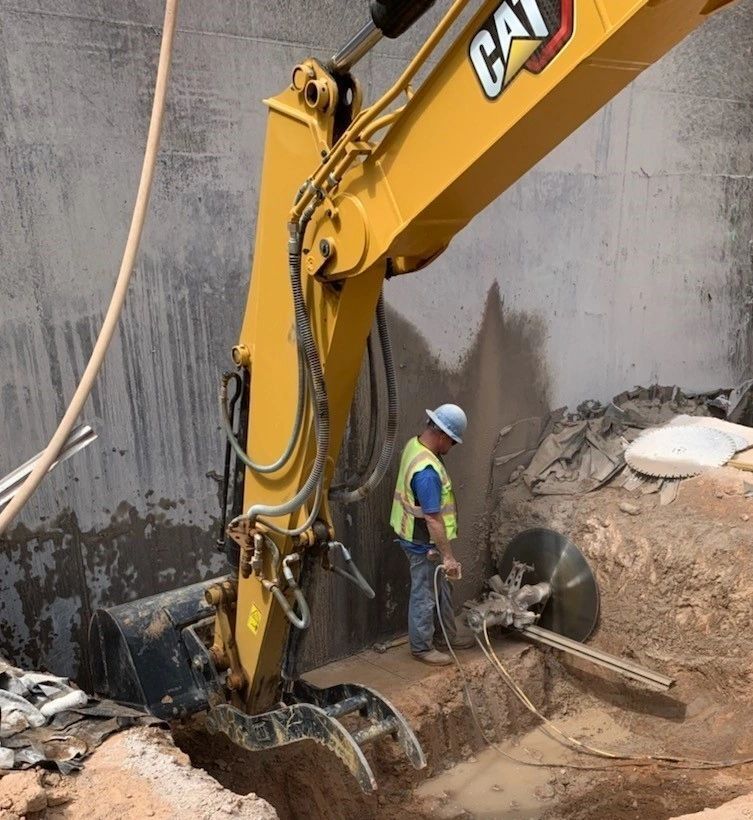 A man is standing next to a yellow cat excavator