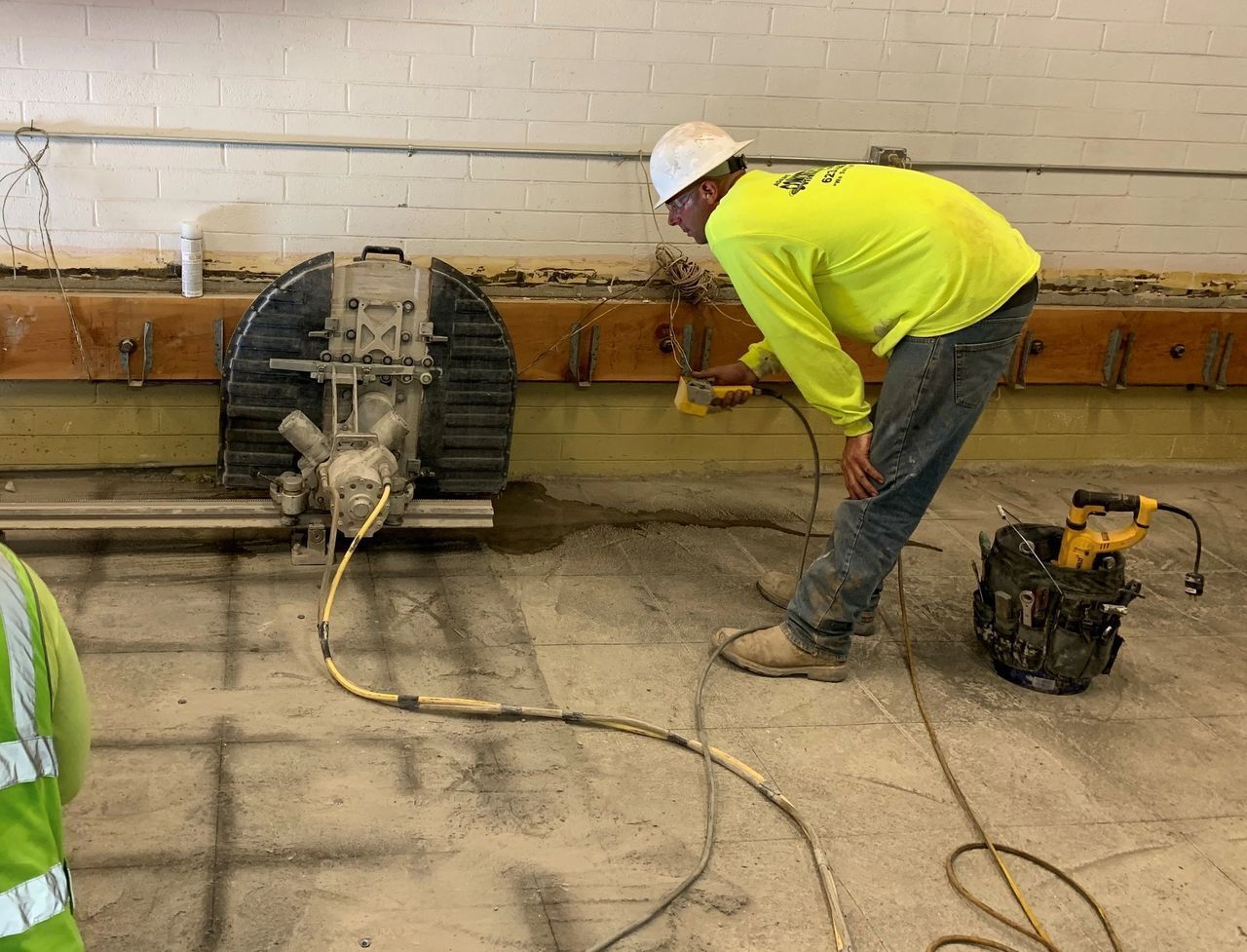 A man is cutting a hole in the floor with a machine.