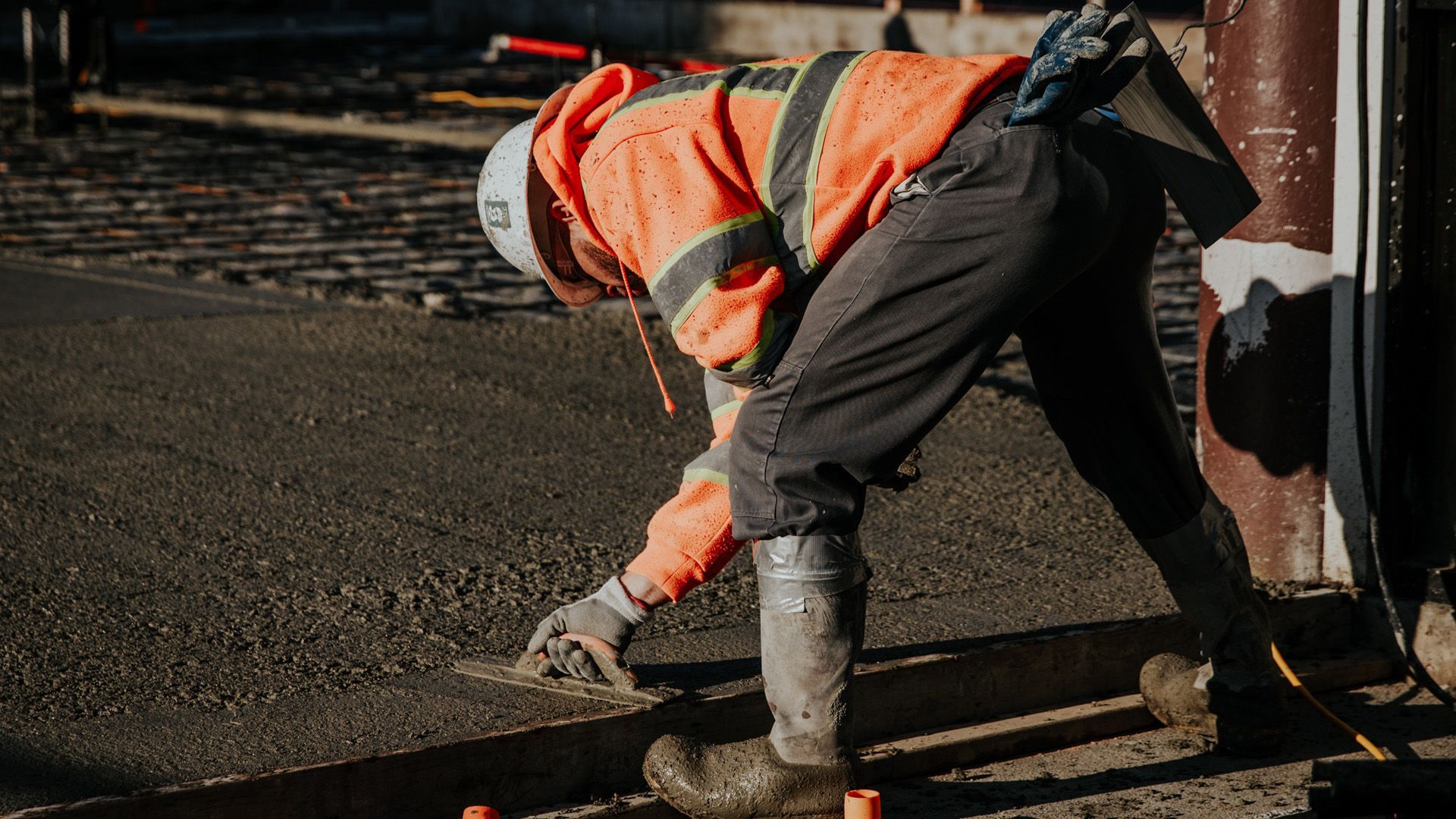 A construction worker is kneeling down on the ground.
