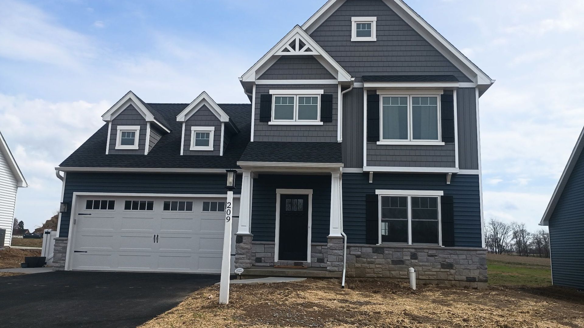 A large blue house with a white garage door is sitting on top of a hill.