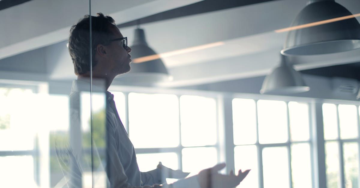 A man is standing in front of a glass wall in an office.
