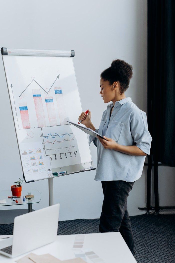 A woman is giving a presentation in front of a flip chart.