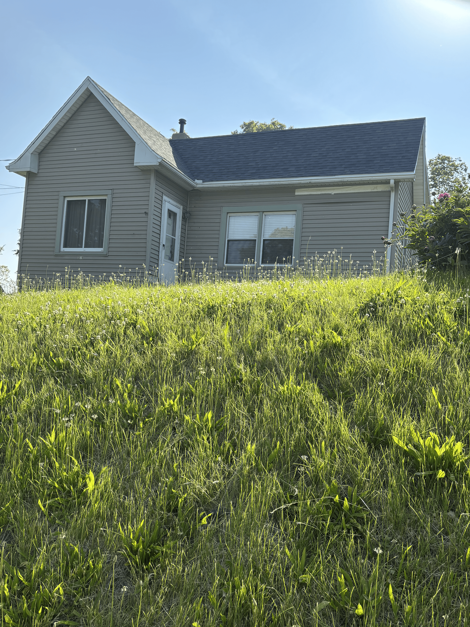 A house is sitting on top of a grassy hill.