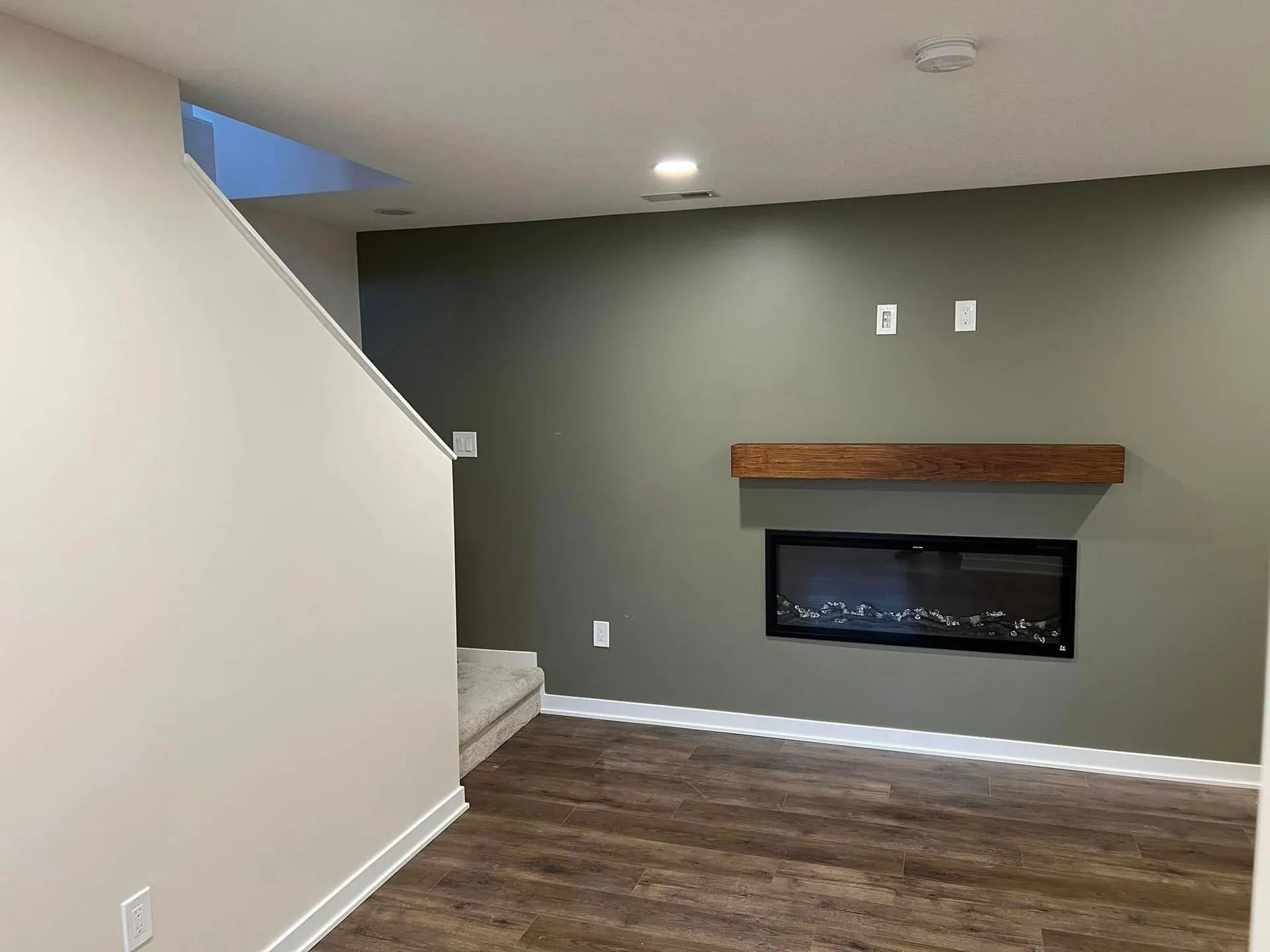 An empty living room with a fireplace and stairs.
