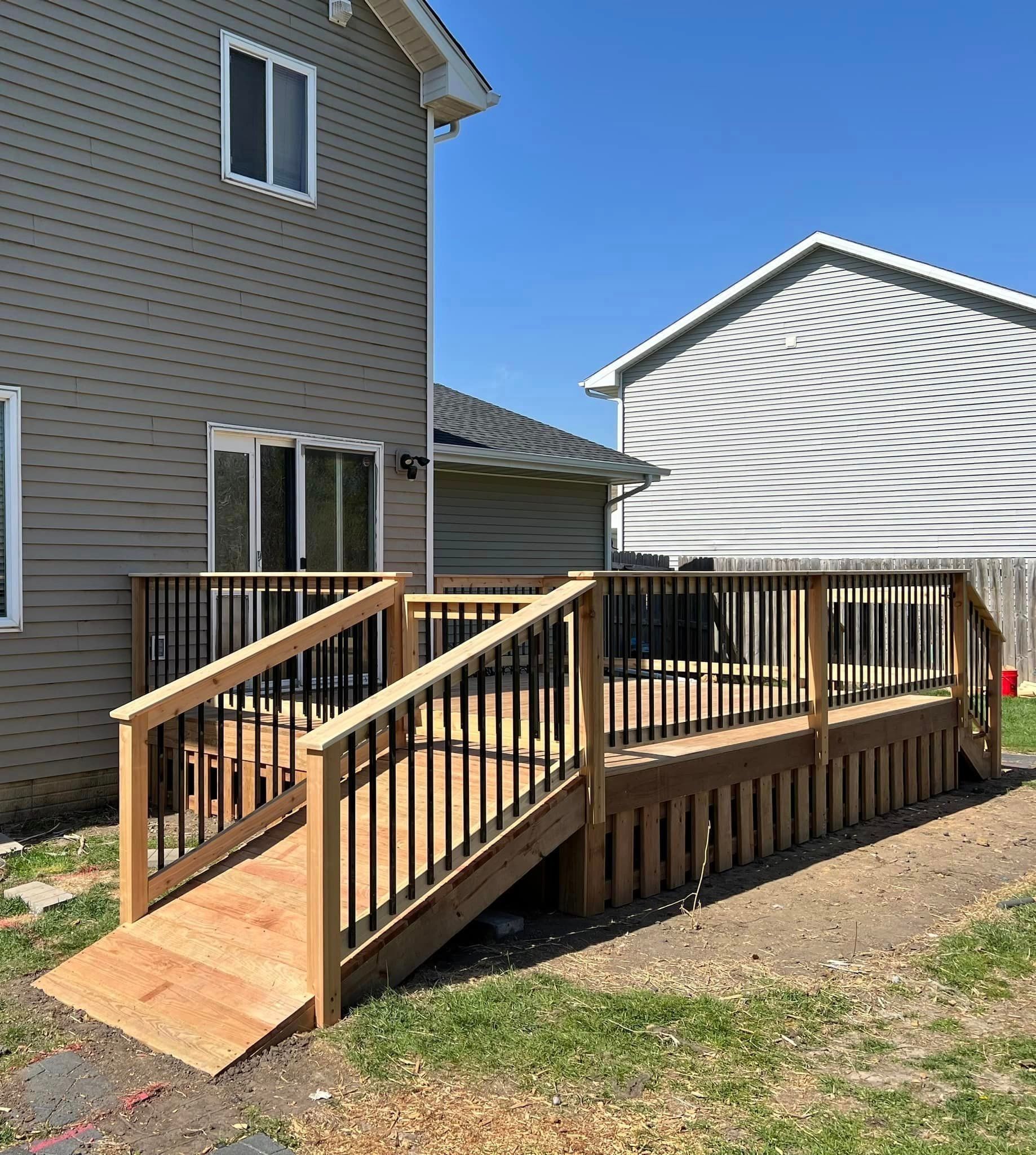 A wooden deck with stairs and a ramp in front of a house.
