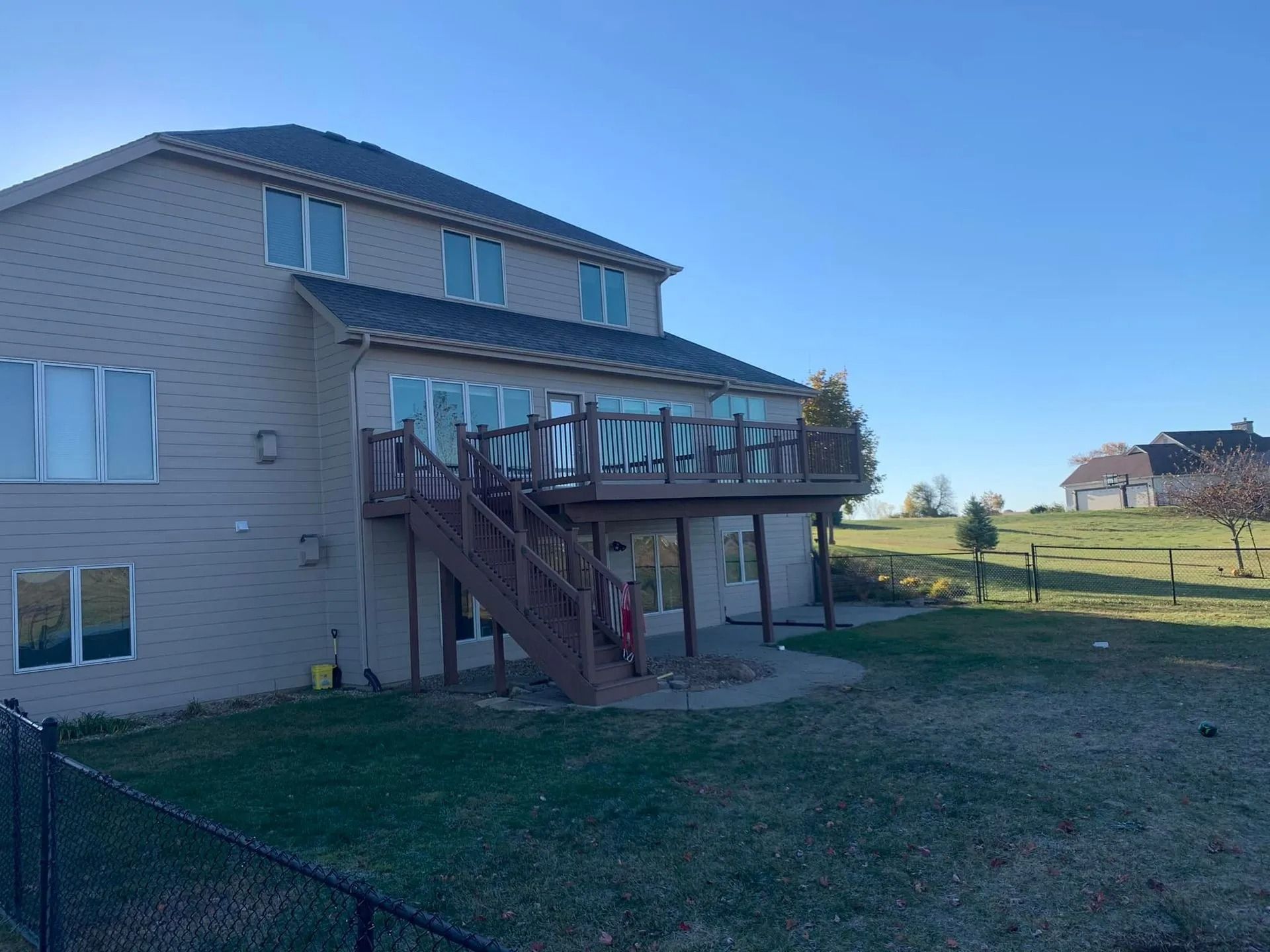 A large house with a large deck and stairs in the backyard.