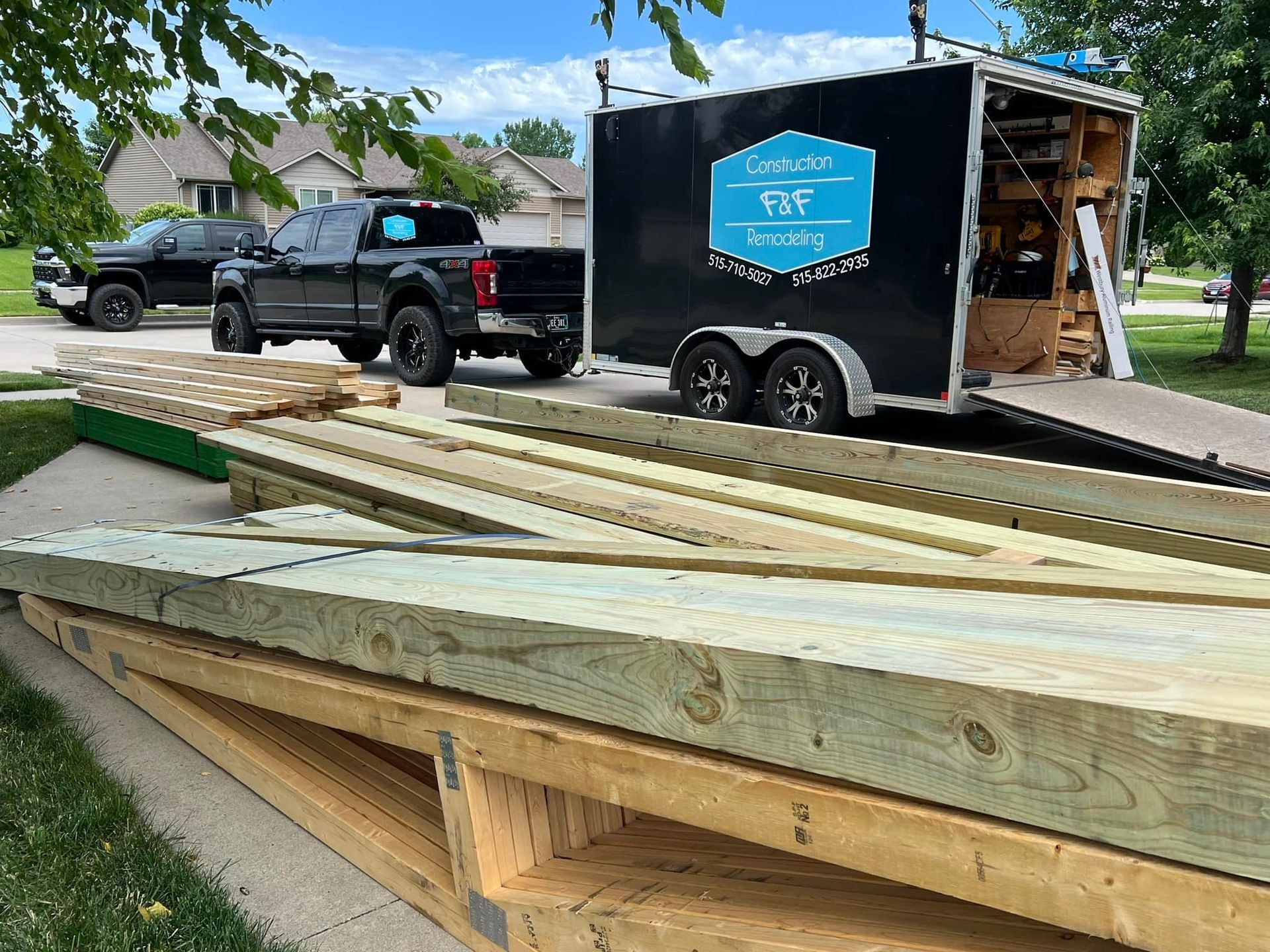 A truck is parked next to a trailer filled with wood.