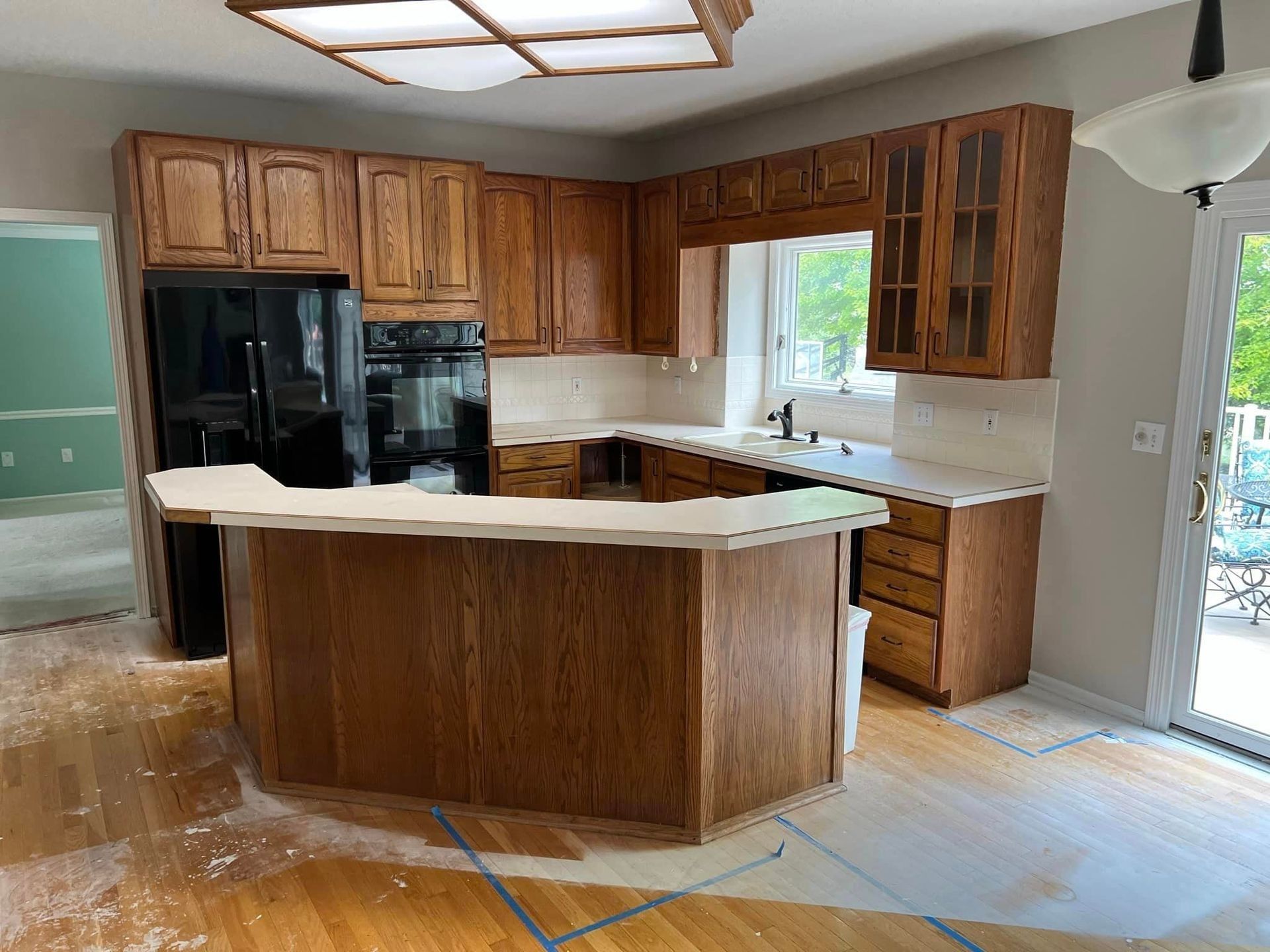 A kitchen with wooden cabinets and a black refrigerator.