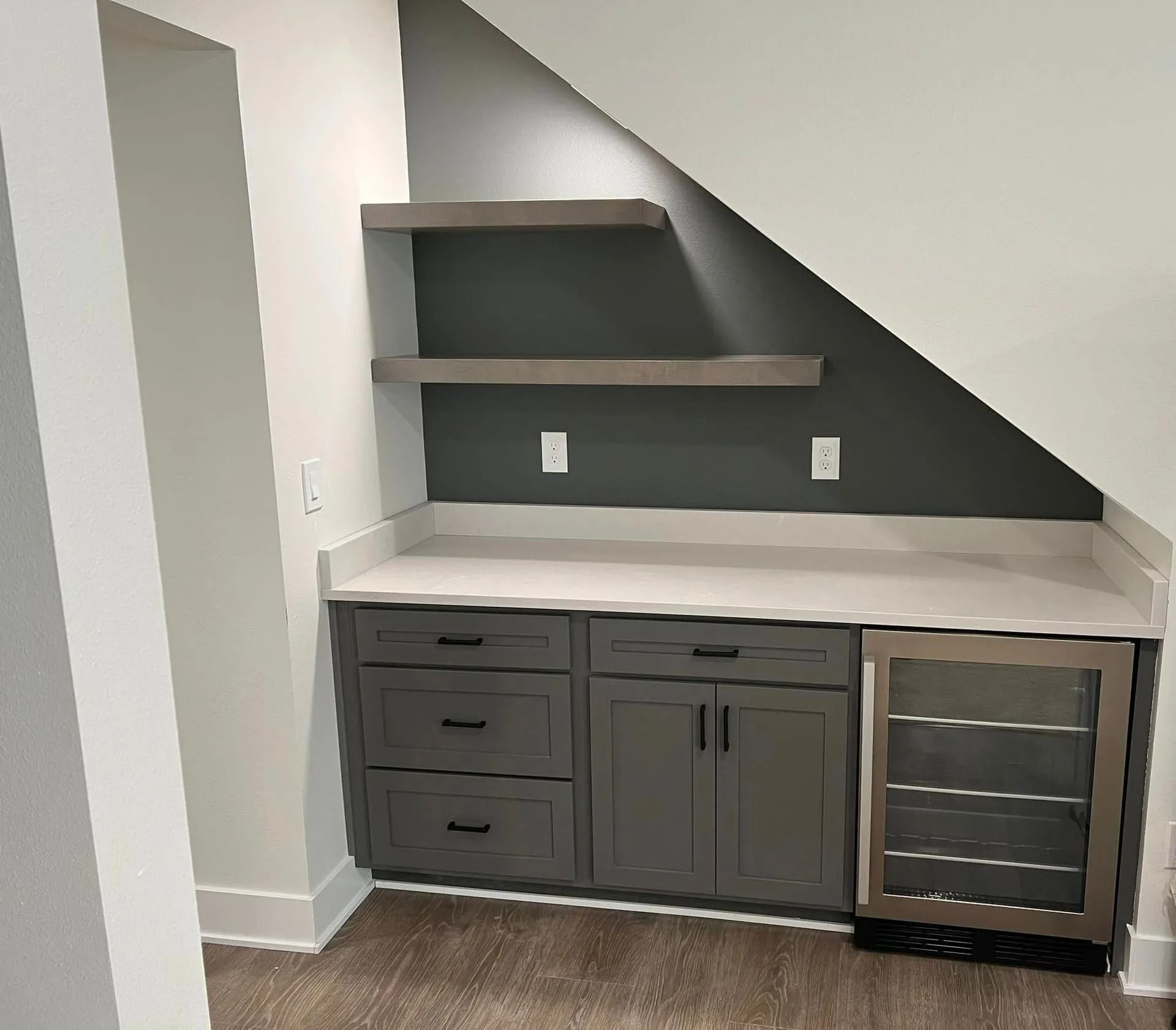 A kitchen with gray cabinets and a stainless steel wine cooler