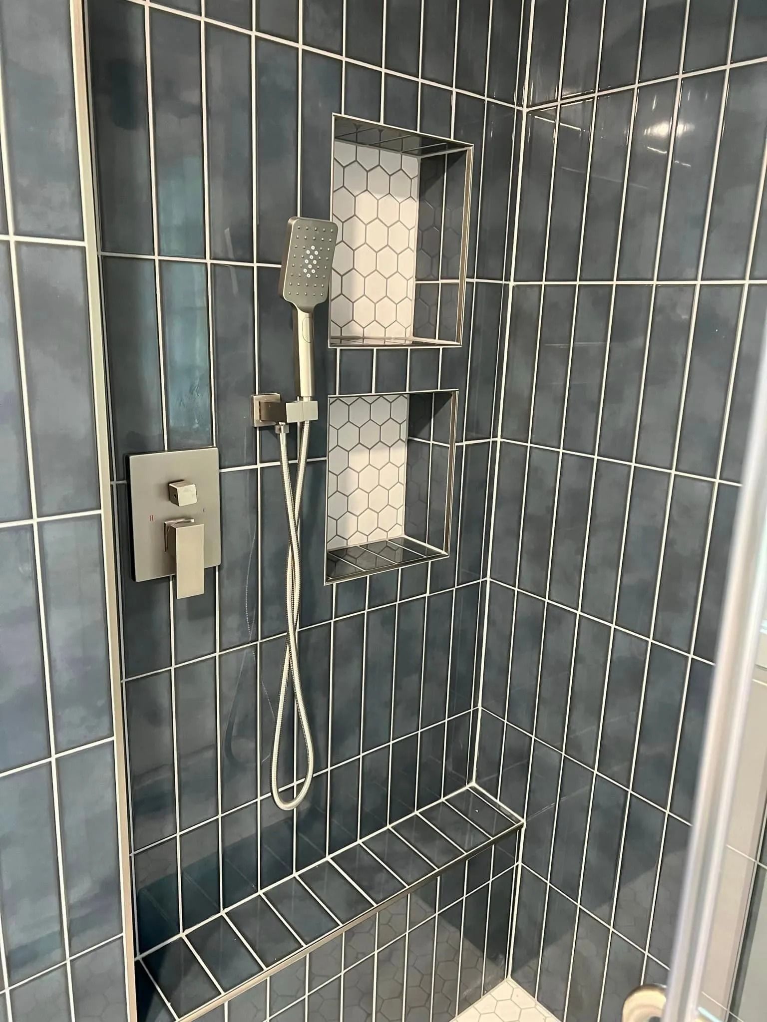 A shower with blue tiles and a shower head.