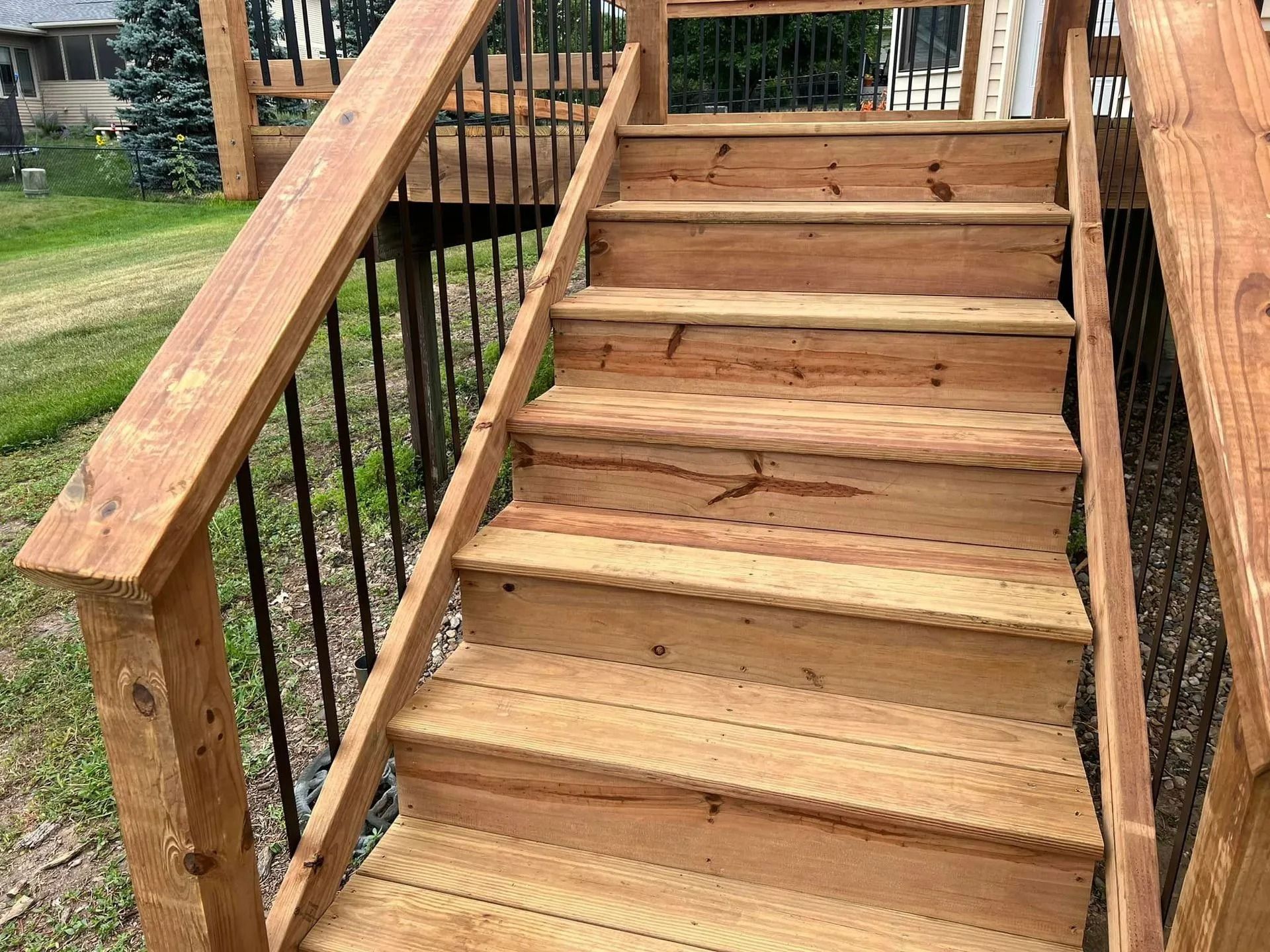 A wooden deck with stairs and a metal railing.