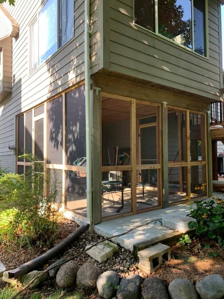 A screened in porch is being built on the side of a house.
