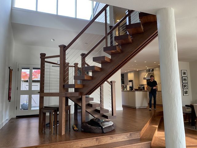a man is walking down a wooden staircase in a house