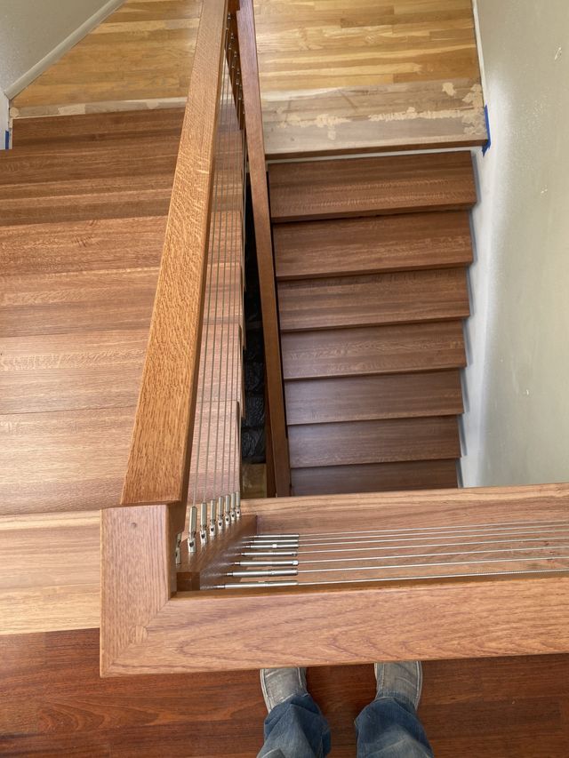a person standing next to a wooden staircase with a metal railing