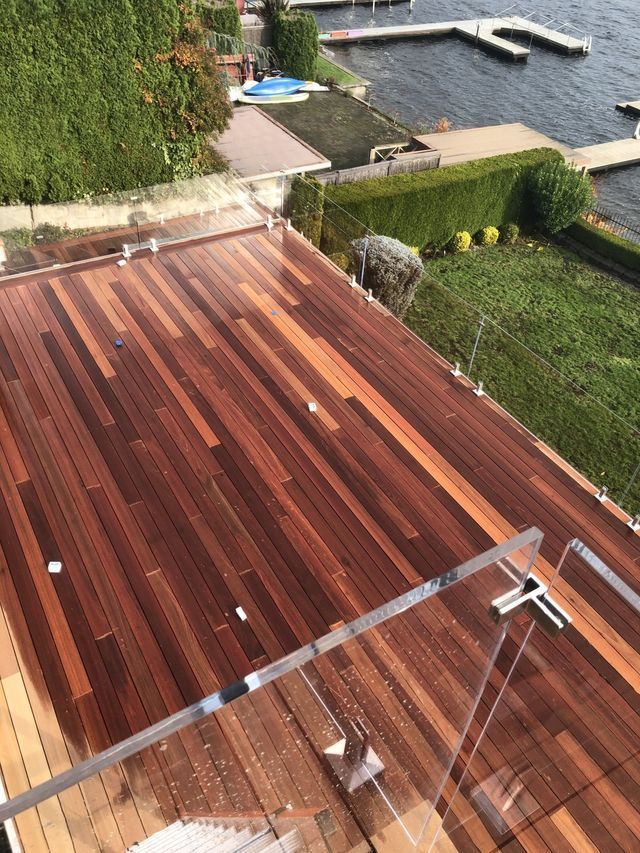 a wooden deck with a glass railing overlooking a body of water .