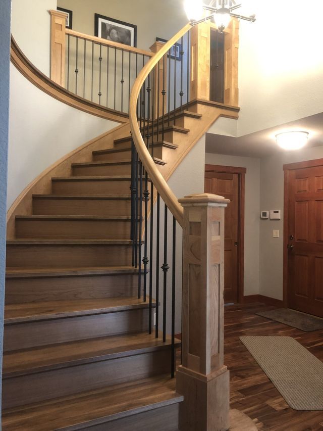 a curved wooden staircase with a metal railing
