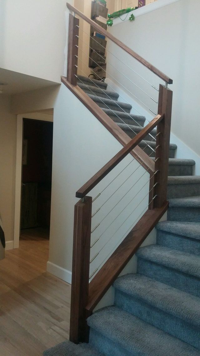a staircase with a wooden railing and a wire railing