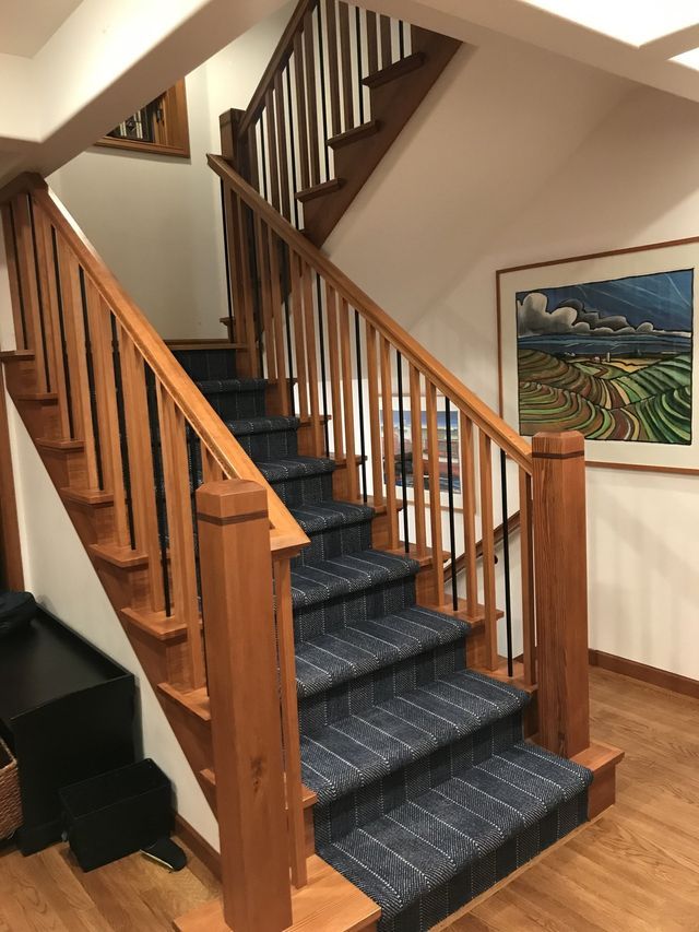 a wooden staircase with blue carpet and a picture on the wall