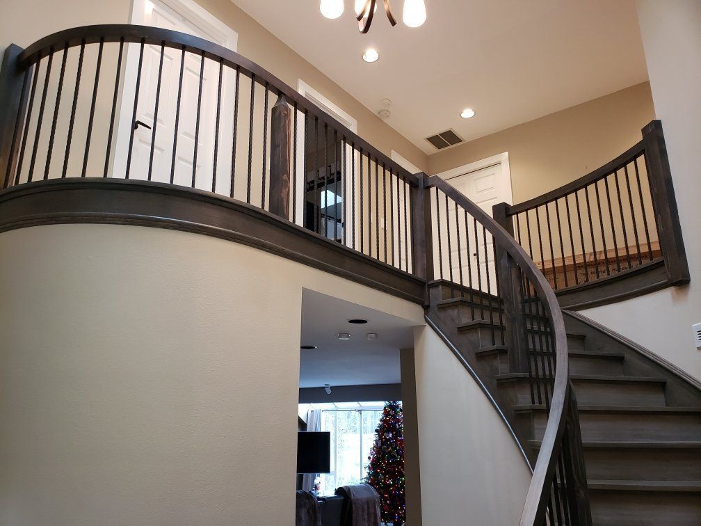 a curved staircase in a house with a christmas tree in the background .