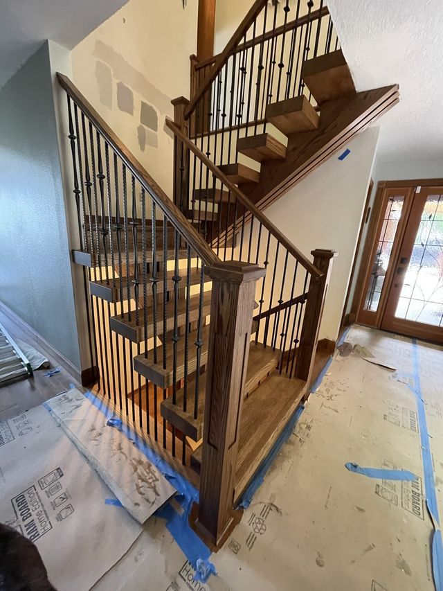a wooden staircase with a metal railing is being painted in a house .