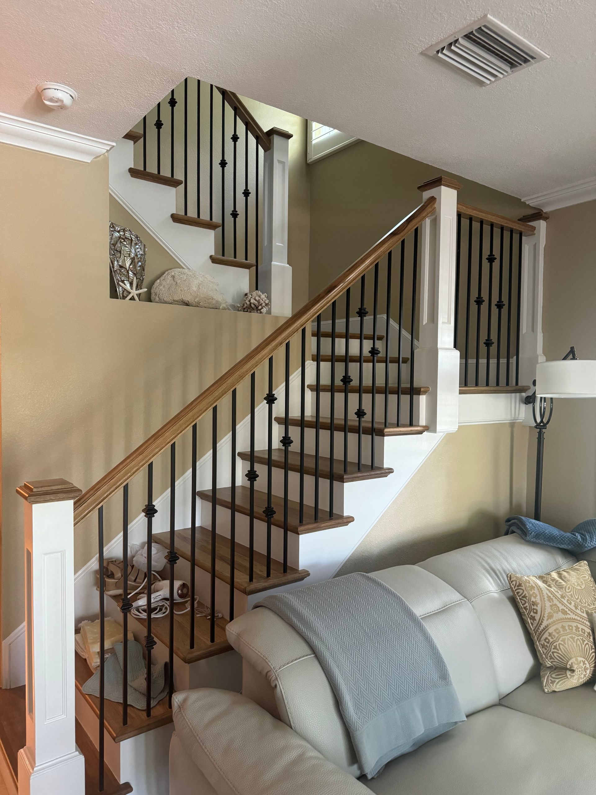 A living room with a couch and stairs leading up to the second floor.