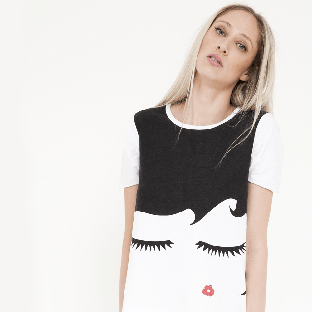 Uma mulher vestindo uma camisa preta e branca com o desenho de um rosto de mulher nela