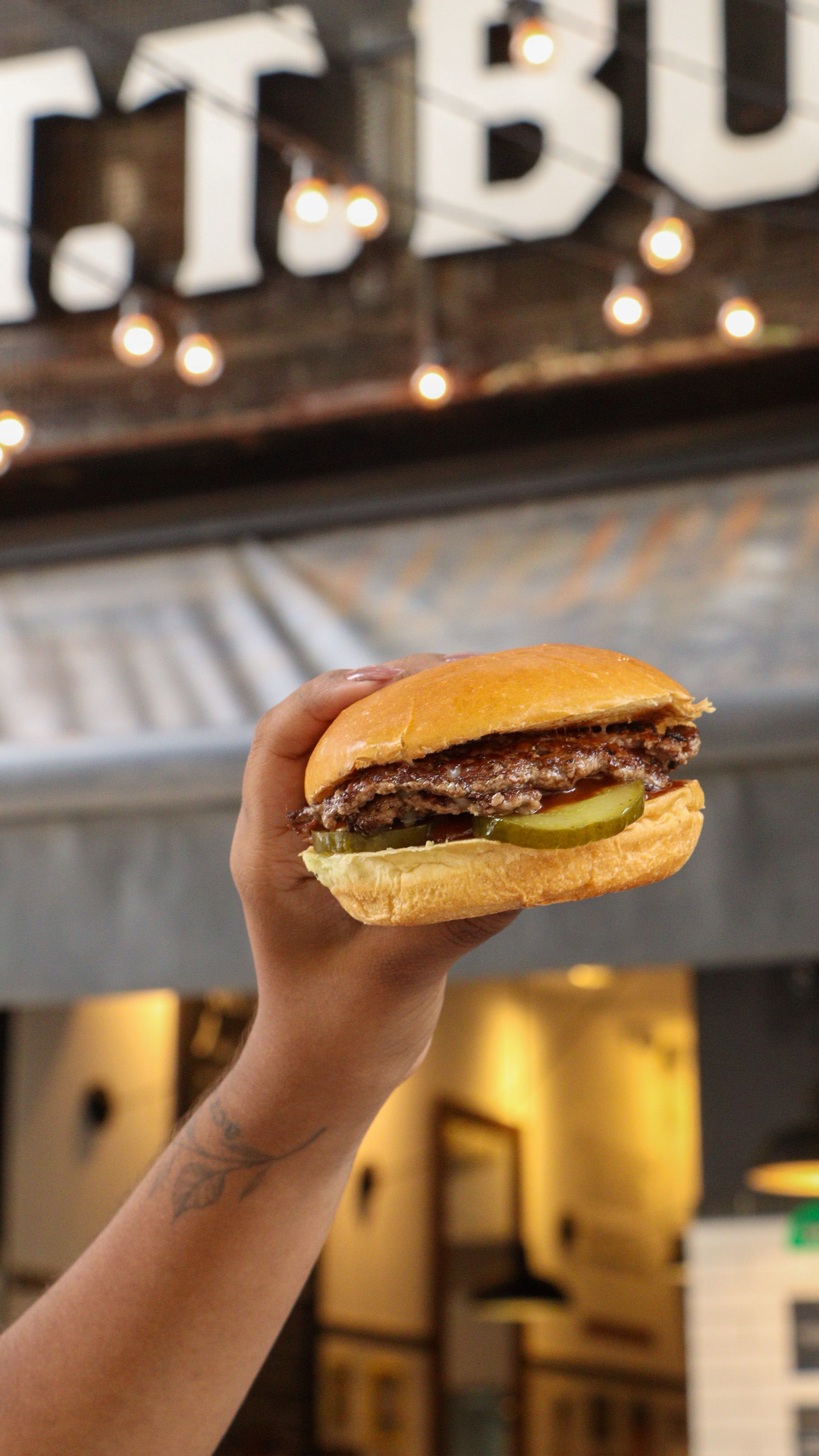 Um homem está segurando um hambúrguer na frente de uma multidão de pessoas.