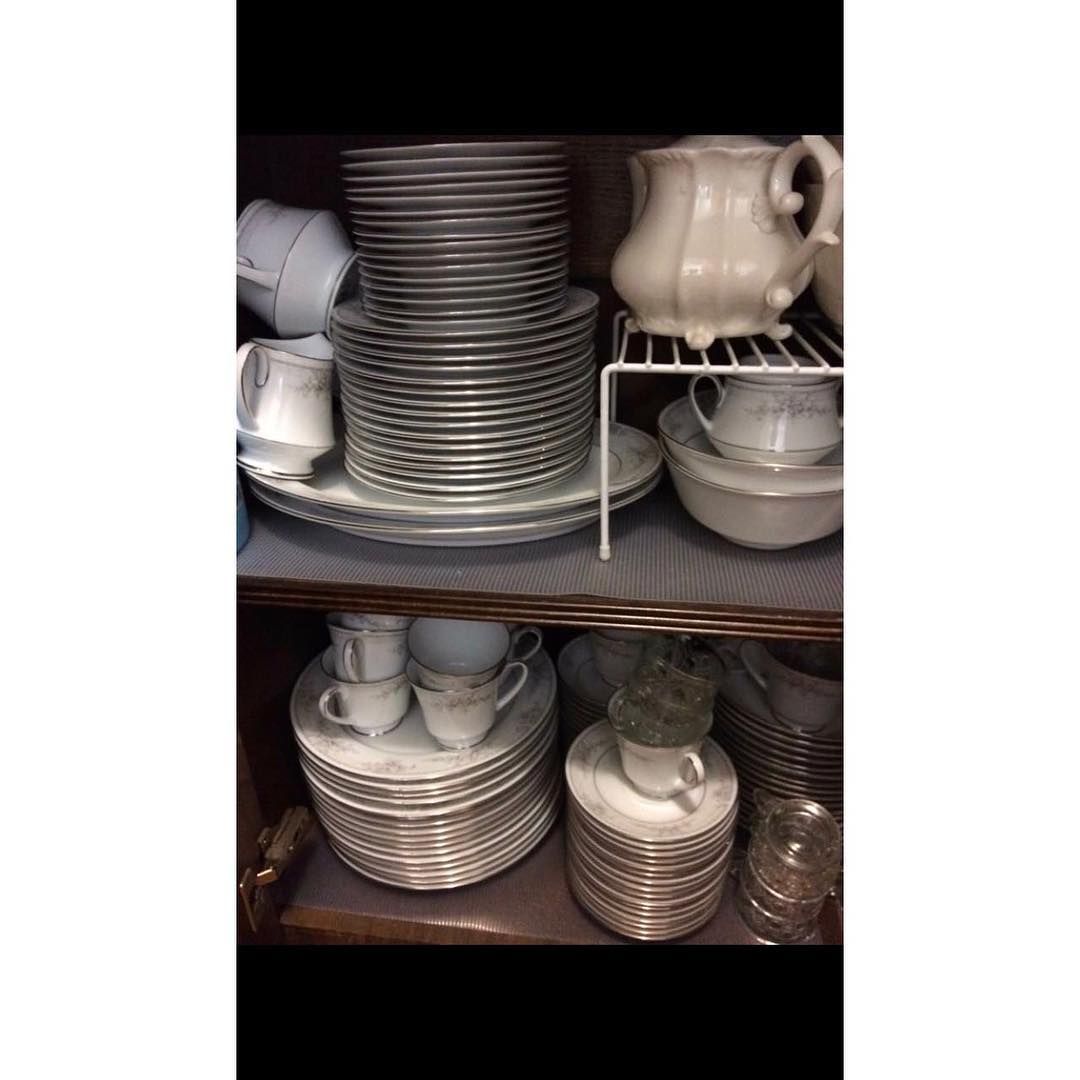 A cabinet filled with stacks of white and gray patterned plates, bowls, cups, and a pitcher.