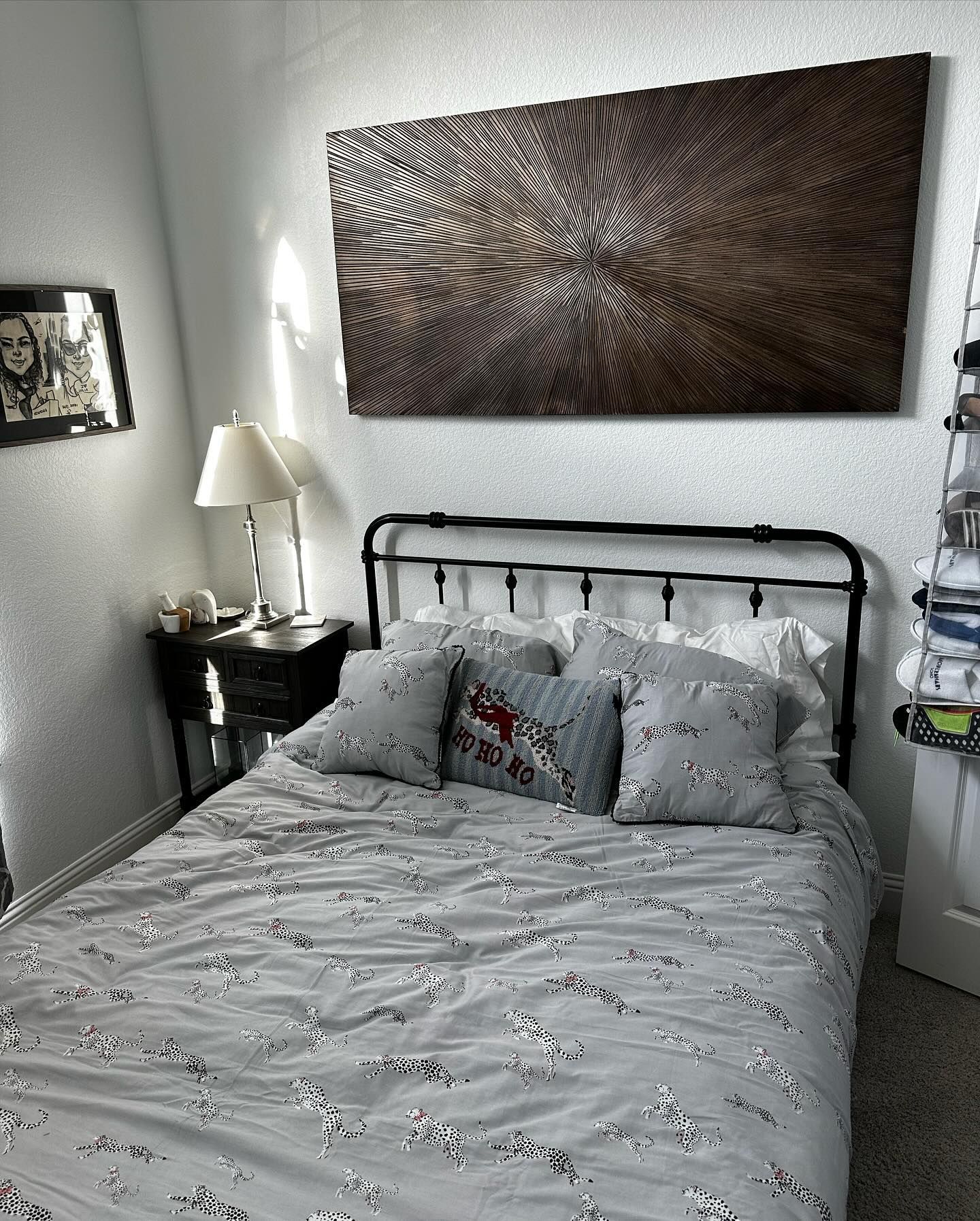 Bedroom with a black metal bed, gray bedding, and a large abstract artwork above the bed.