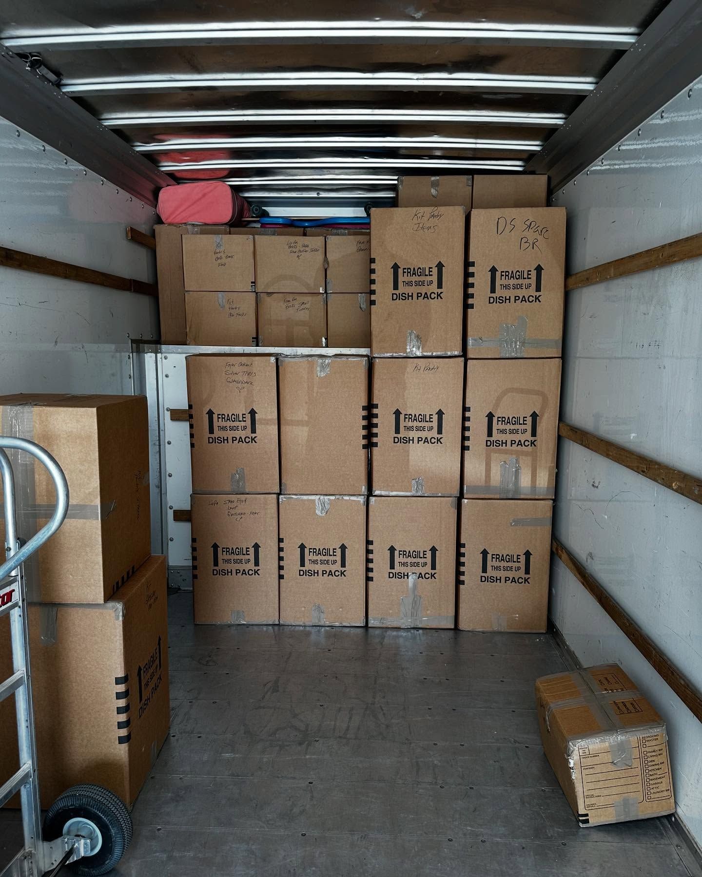 Interior of a moving truck packed with cardboard boxes, some labeled 