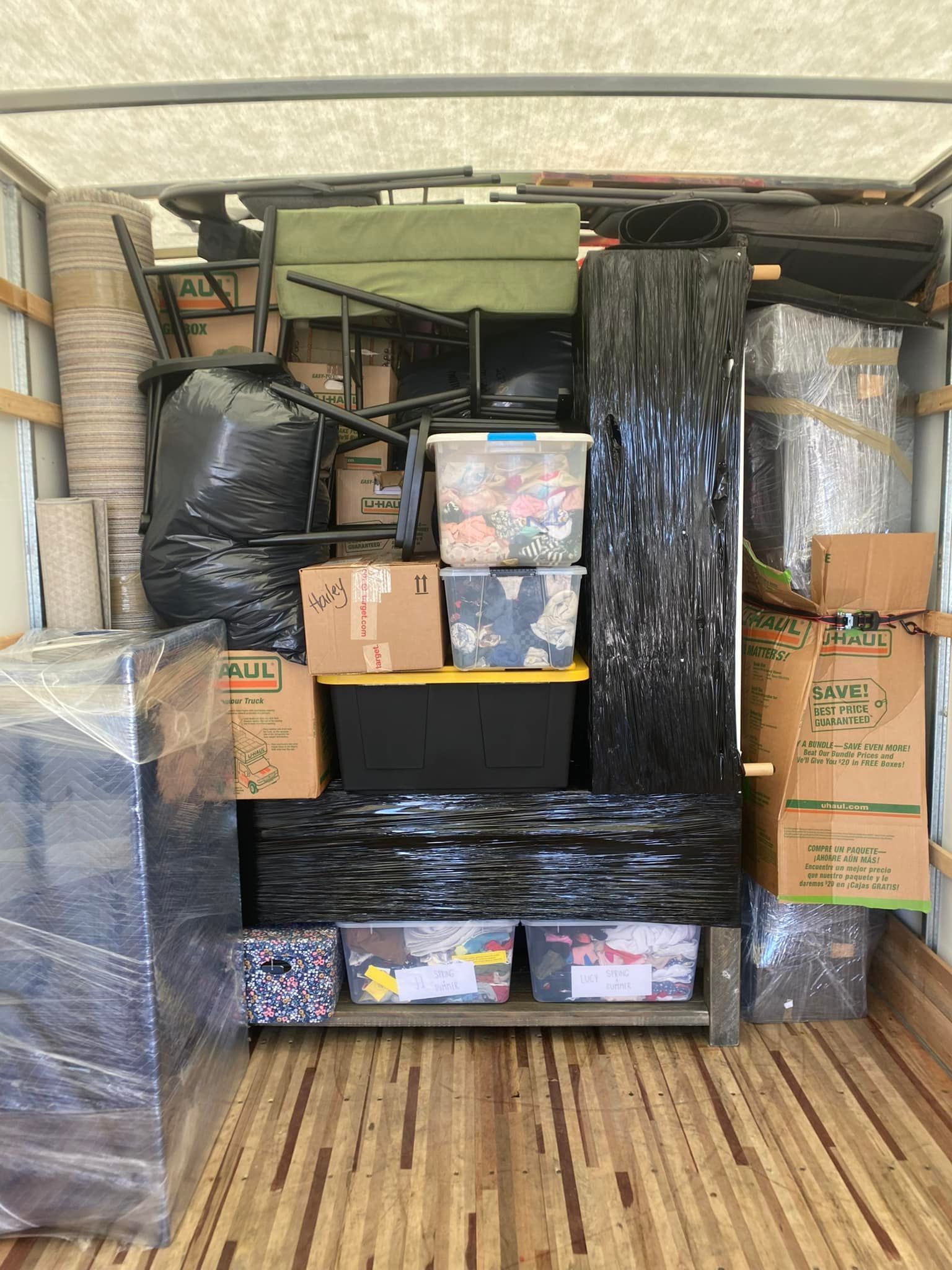 Moving truck interior filled with packed boxes, furniture, and covered items.