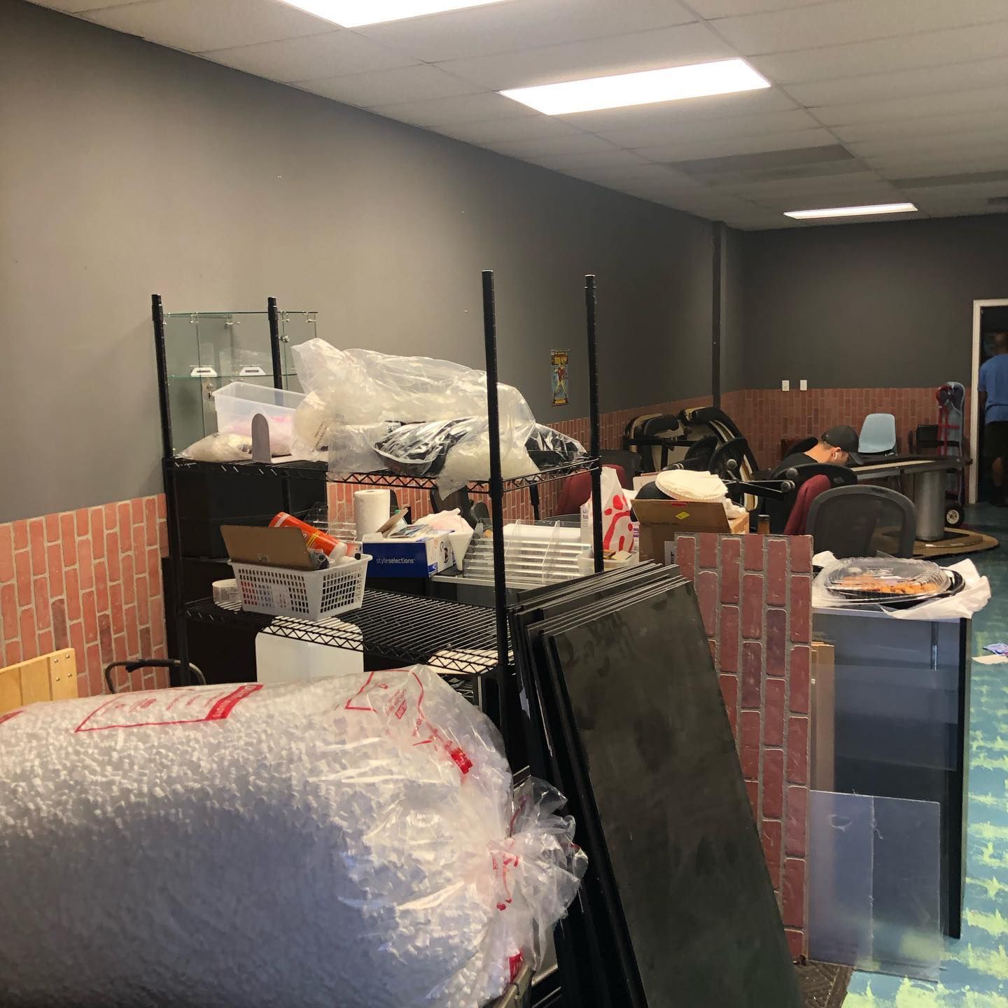 Cluttered interior of a room, with various objects, and a person in the doorway.