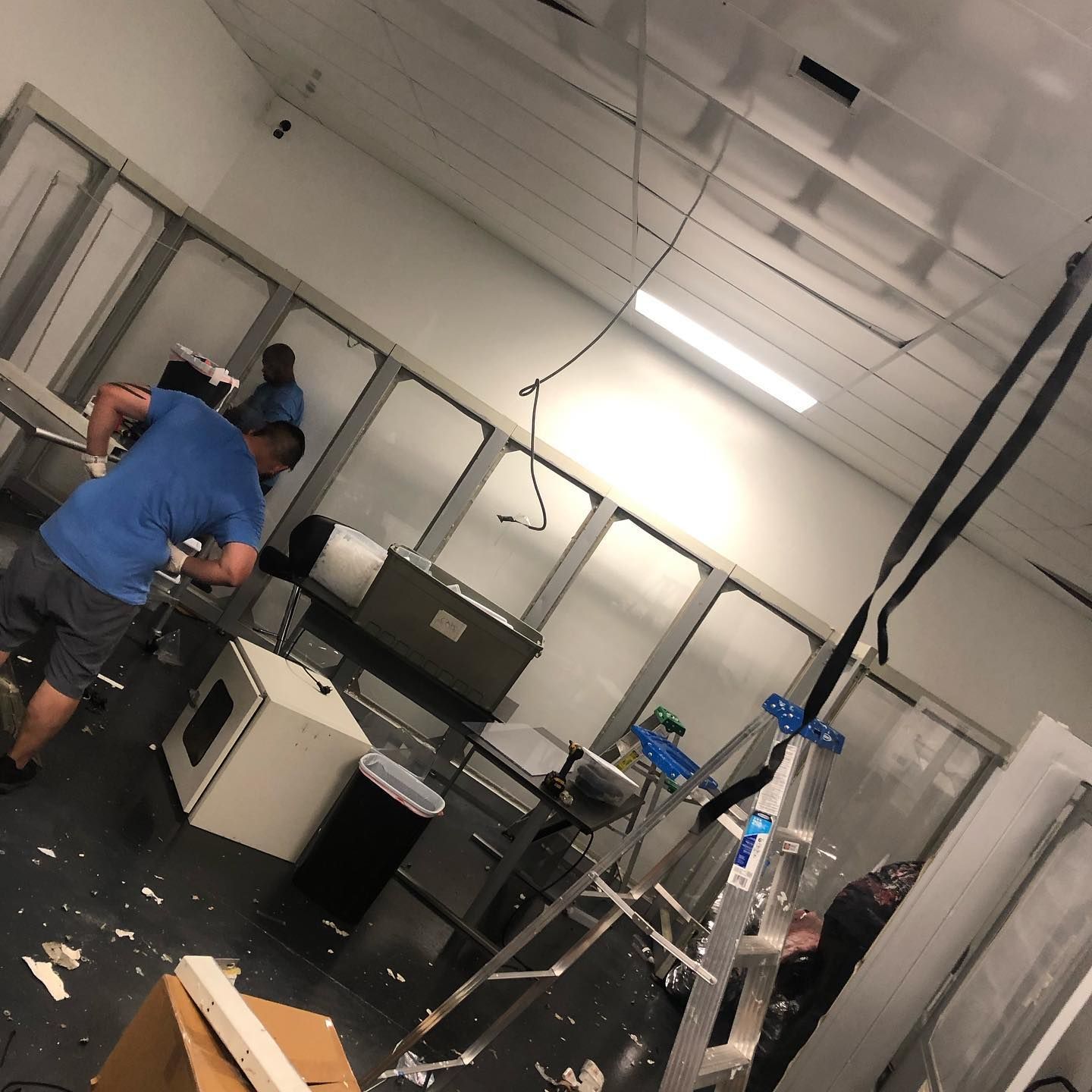 People working in a sterile room, with equipment and a ladder, possibly during construction or maintenance.