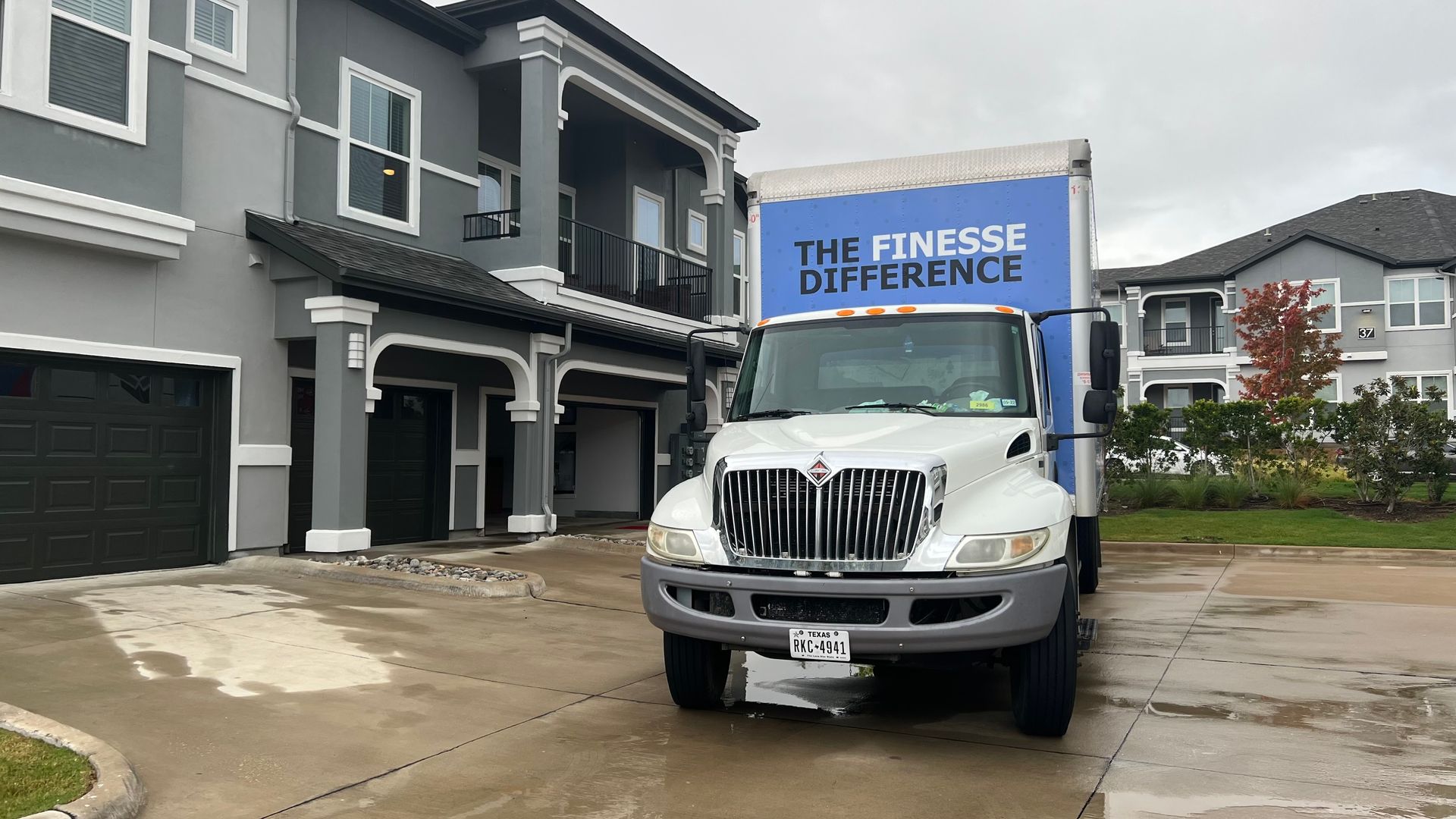 Moving truck parked in front of a gray building. 
