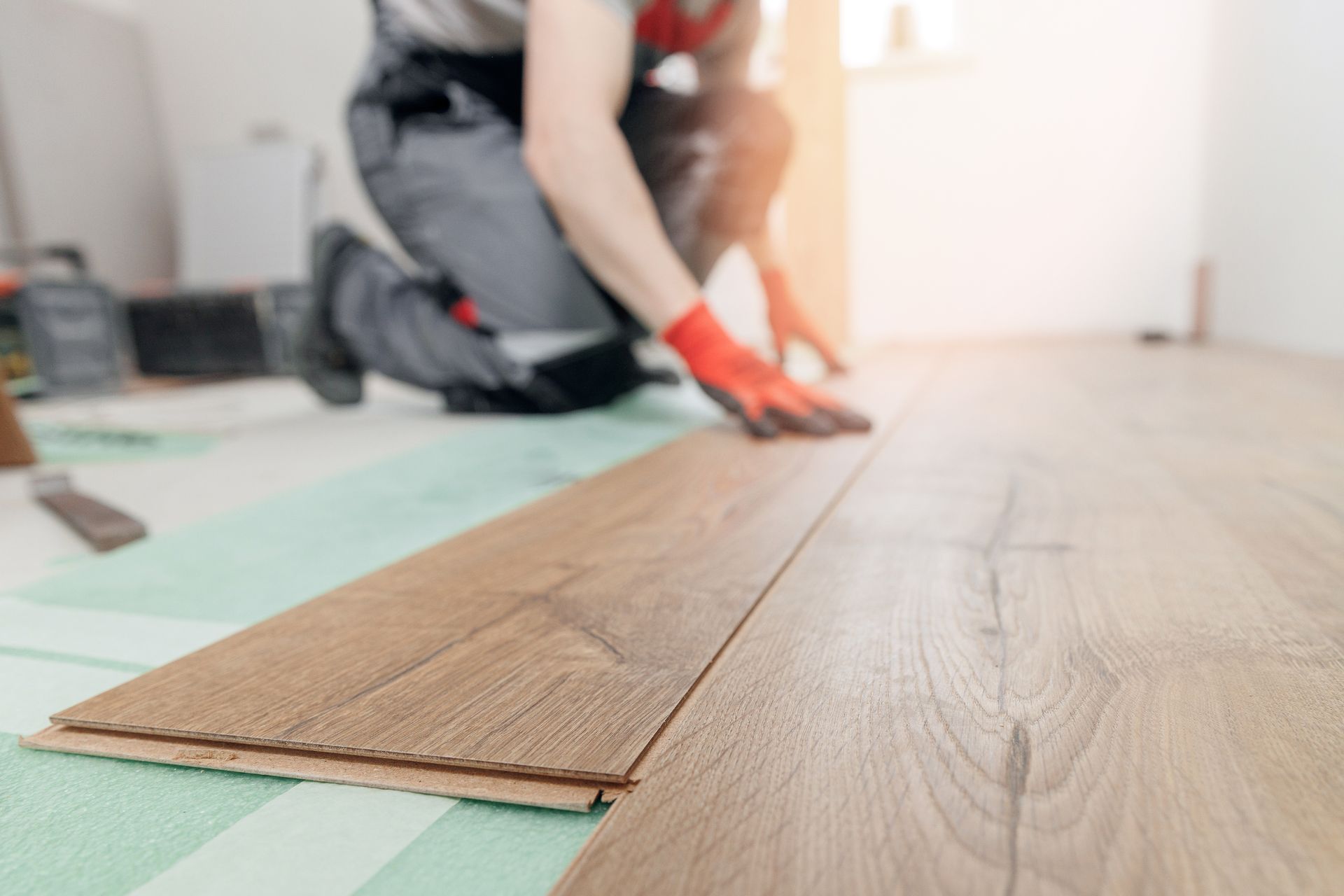 Un homme installe un parquet dans une pièce.